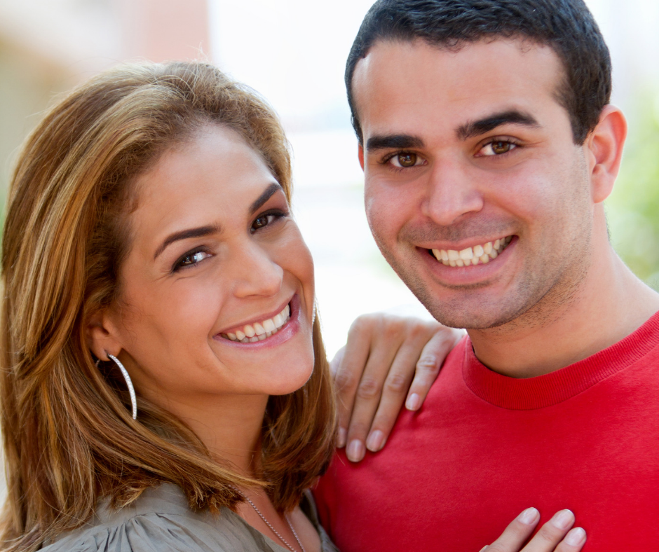 Hispanic couple, male and female embracing and smiling